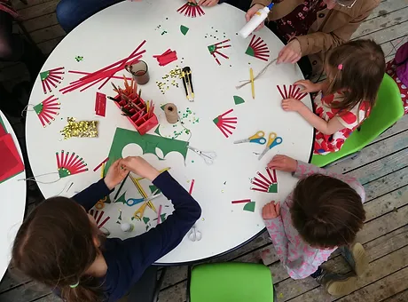 Children sitting around a table, crafting Christmas decorations
